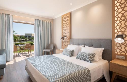 a hotel room with a bed and a balcony at Pilot Beach Resort in Georgioupolis