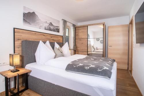 a bedroom with a large white bed with a wooden headboard at Apart Dahoam in Wiesing