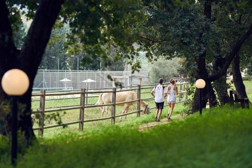 a man and a woman walking by a fence with a cow at Pilot Beach Resort in Georgioupolis