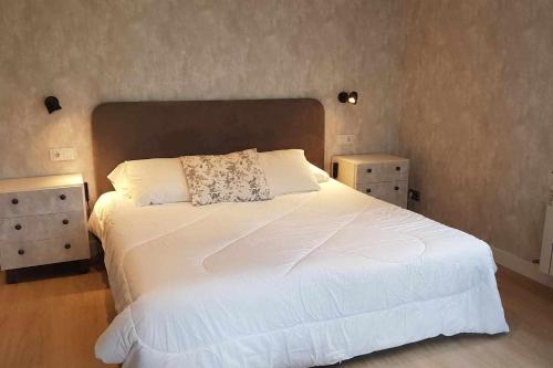 a bedroom with a large white bed with two night stands at Refugio Mirador en Casa Rural Camp de Claror in Aixirivall