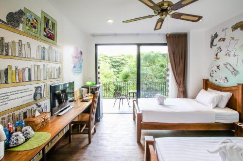 a bedroom with two beds and a desk with a tv at Rain Tree Khao Yai Hotel in Phayayen
