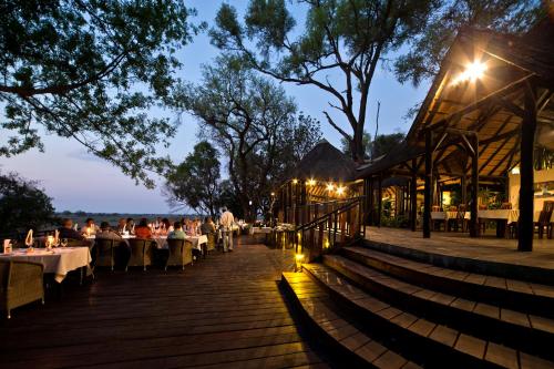 a restaurant with people sitting at tables at night at Namushasha River Camping2Go in Kongola