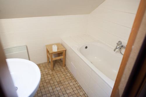 a bathroom with a tub and a toilet and a table at Penzion Krizky in Malá Skála