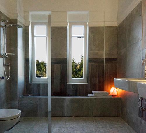 a bathroom with a shower and a tub and two windows at Lovely apartm.near airport in Kardiá