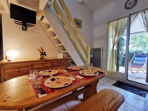 un comedor con una mesa de madera y una escalera en Les Lavandines -Coquette Maison de Vacances - 400 m de la plage - Grande Terrasse - 2 chambres - 2 salles de bain - Tout confort en Argelès-sur-Mer