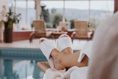 a woman in white shoes sitting next to a swimming pool at PANORAMA Hotel Heimbuchenthal in Heimbuchenthal