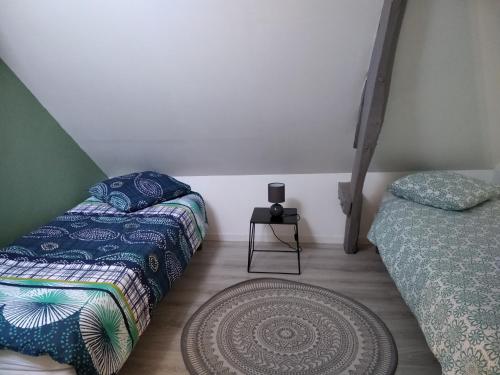 a bedroom with two beds and a rug on the floor at Coquelicot in Criquetot-lʼEsneval