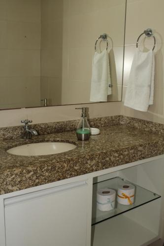 un bancone del bagno con lavandino e specchio di Lindo Apartamento pé na areia com serviço de limpeza a Lauro de Freitas