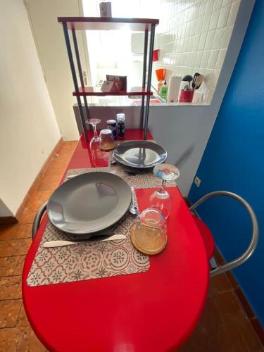 une table rouge avec deux assiettes et des verres dessus dans l'établissement Pause Paisible à Blois « Comme à « BROOKLYN », à Blois