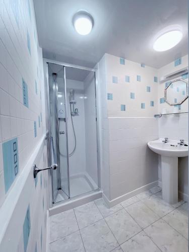 a white bathroom with a shower and a sink at OYO Lily Hotel Blackpool in Blackpool