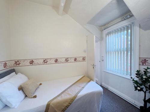 a white bedroom with a bed and a window at OYO Lily Hotel Blackpool in Blackpool