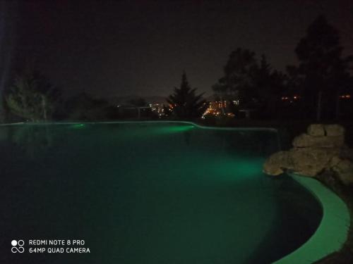 a swimming pool at night with green illumination at Posada El Antiguo Refugio potrero de los funes in Potrero de los Funes
