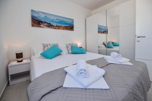 a white bedroom with two beds with towels on them at Pool Apartments Funtastic C in Novalja
