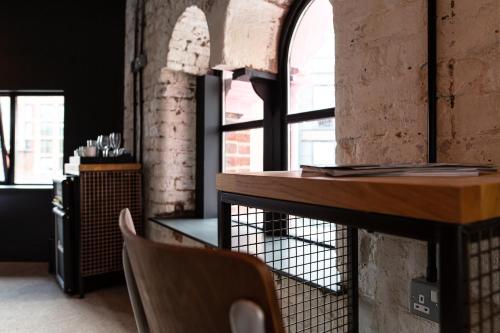 einen Tisch und Stühle in einem Zimmer mit Fenstern in der Unterkunft The Baltic Hotel in Liverpool