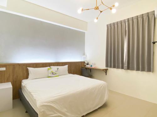 a bedroom with a white bed and a window at Kun Inn - Nandao in Taitung City