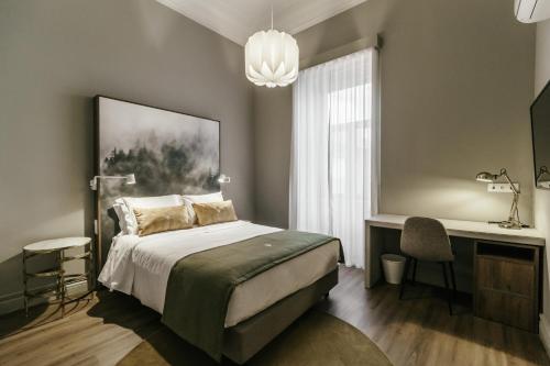 a bedroom with a bed and a desk and a window at Royal Collection Covilhã in Covilhã