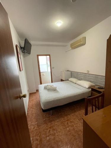 a bedroom with a bed and a desk and a window at Pensión Fortea in Zaragoza