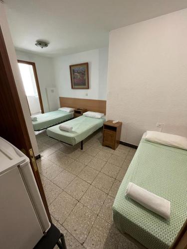 a room with three beds in a room at Pensión Fortea in Zaragoza