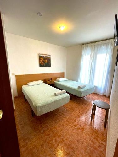 a hotel room with two beds and a stool at Pensión Fortea in Zaragoza