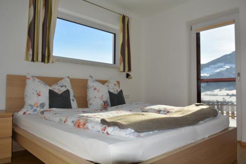 ein Bett in einem Schlafzimmer mit zwei Fenstern in der Unterkunft Ferienwohnung Sunnseitn in Haus im Ennstal