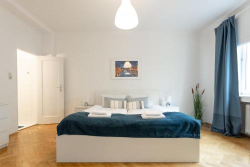 a white bedroom with a large bed with blue blanket at City Center Operastreet Apartment "Italy" in Vienna