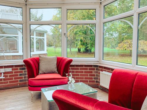 a living room with red chairs and windows at Trivelles Waterhall Country Gatwick Hotel & airport parking in Crawley