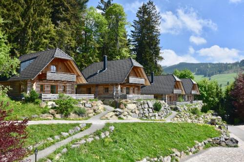 una casa di tronchi tra le montagne con un vialetto di ghiaia di Hotel & Chalets Herrihof a Todtnauberg