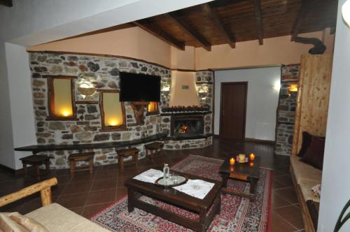 a living room with a fireplace and a stone wall at Pasithei in Karpenision