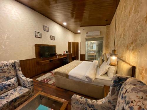 a bedroom with a bed and two chairs and a tv at Royal Castle in Kasol