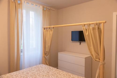 a bedroom with a bed and a tv and curtains at "Country House il Brolo" in Polpenazze del Garda