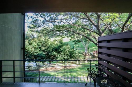 a balcony with a bench and a view of a park at Rain Tree Khao Yai Hotel in Phayayen