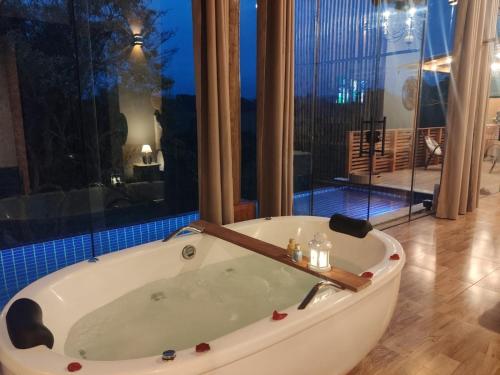 a bath tub in a room with a large window at Chalé Tucano super Luxo in Cunha