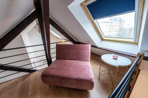 a living room with a red chair and a table at Le Magnifique Appart'Hotel Le Gatsby in Saint-Quentin