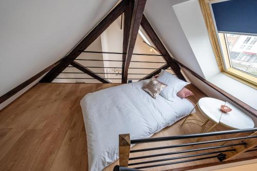 ein Schlafzimmer mit einem weißen Bett im Dachgeschoss in der Unterkunft Le Magnifique Appart'Hotel Le Gatsby in Saint-Quentin