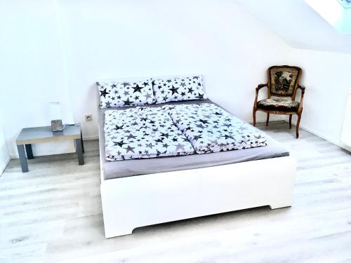 a white bed in a room with a chair at Ferienwohnung Bellevue in Saarbrücken
