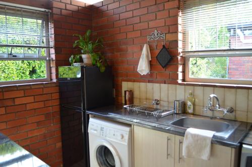 a kitchen with a sink and a washing machine at The Red Wine Cottage in Stellenbosch