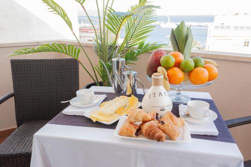 a table with a plate of pastries and a bowl of fruit at Oh Nice Ulises Ceuta in Ceuta