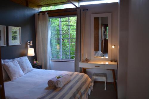 a bedroom with a bed and a mirror and a window at The Red Wine Cottage in Stellenbosch