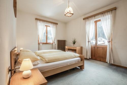 1 dormitorio con 1 cama y 1 mesa con lámpara en Affittacamere Blank, en Arabba