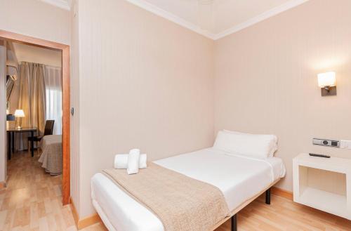 a white bedroom with a bed with two candles on it at Oh Nice Ulises Ceuta in Ceuta