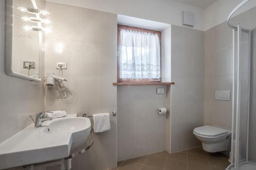 baño con lavabo y aseo y ventana en Affittacamere Blank, en Arabba