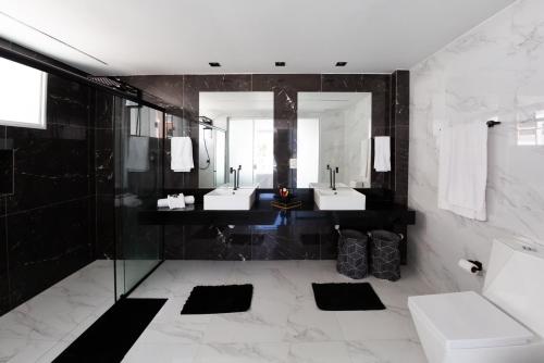 La salle de bains est pourvue de 2 lavabos et d'un miroir. dans l'établissement Alto padrão no coração de Jurerê Internacional !!!, à Florianópolis