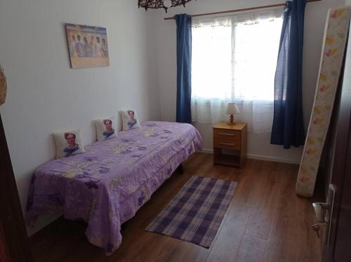 a bedroom with a bed with a purple blanket and a window at Hermosa casa en Ocean Park in Ocean Park
