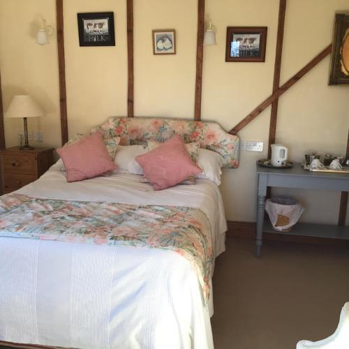 a bedroom with a bed with pink pillows on it at Barn Park Farm, Bed and Breakfast in Honiton