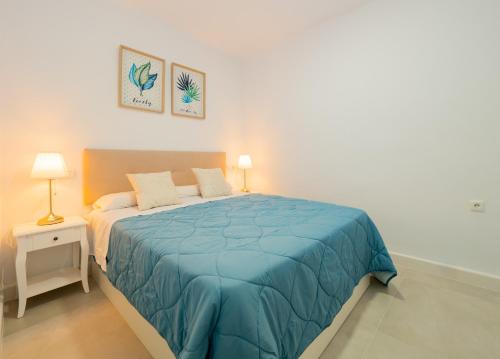 um quarto com uma cama com um cobertor azul em Cubo's Urban Miranda Apartment em Cártama