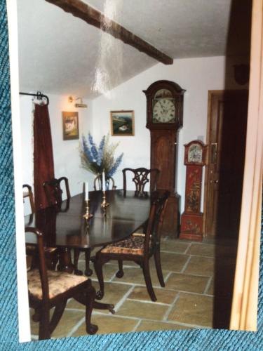 a dining room with a table and a grandfather clock at Barn Park Farm, Bed and Breakfast in Honiton