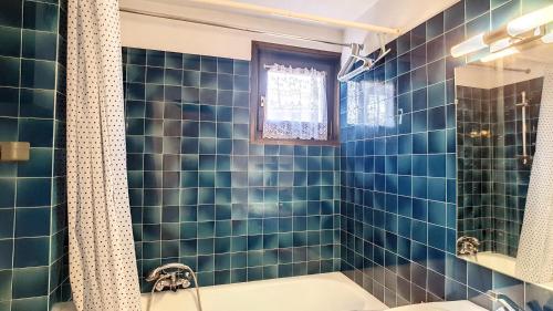 La salle de bains est pourvue de carrelage bleu, d'une baignoire et d'une douche. dans l'établissement STUDIO LUMINEUX -SAINT JEAN D'AULPS STATION - 5 Personnes- RELAIS S29, à Saint-Jean-dʼAulps