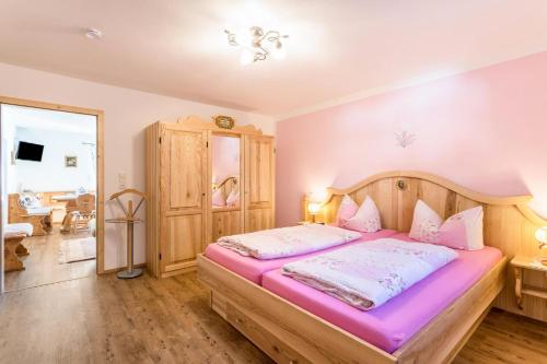 a bedroom with a wooden bed with pink sheets at Ferienwohnung Rosenquarz in Mittenwald