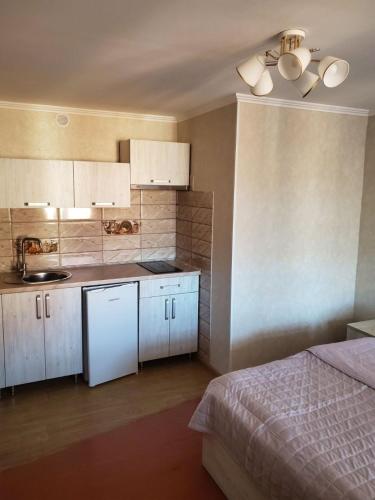 a kitchen with white cabinets and a bed in a room at Апартаменти "Ілона" в центрі Східниці in Skhidnitsa