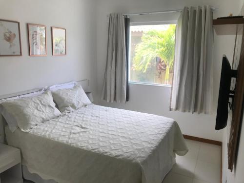 una camera da letto con un letto bianco e una finestra di Village Verano Guarajuba B4 ACOMODA 6 PESSOAS a Guarajuba